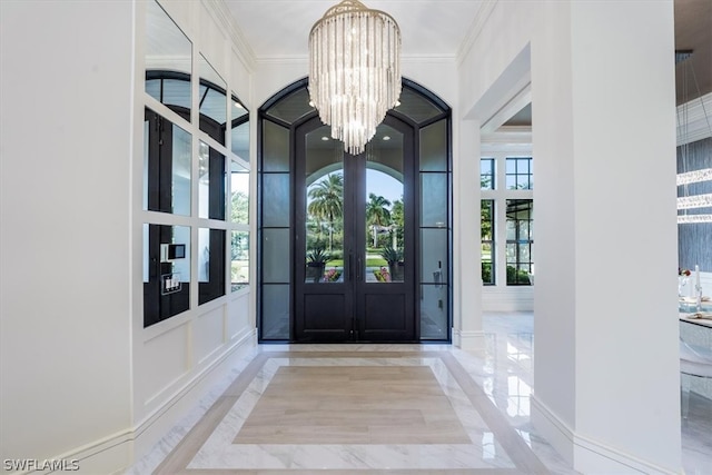 tiled entryway featuring ornamental molding, an inviting chandelier, and french doors