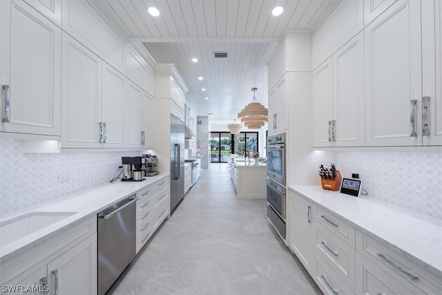 kitchen featuring light stone countertops, backsplash, white cabinetry, and appliances with stainless steel finishes