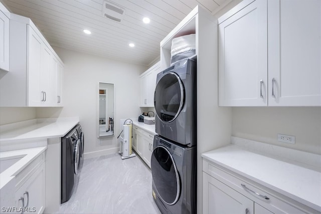 laundry room featuring stacked washing maching and dryer, cabinets, and light tile floors