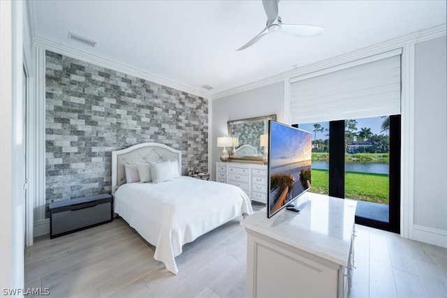 bedroom featuring light hardwood / wood-style floors, crown molding, a water view, access to exterior, and ceiling fan