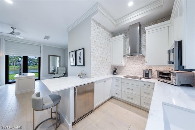 kitchen with backsplash, wall chimney range hood, black electric cooktop, and white cabinets