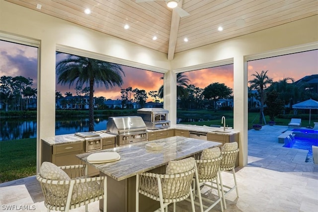 patio terrace at dusk featuring a water view, sink, and area for grilling