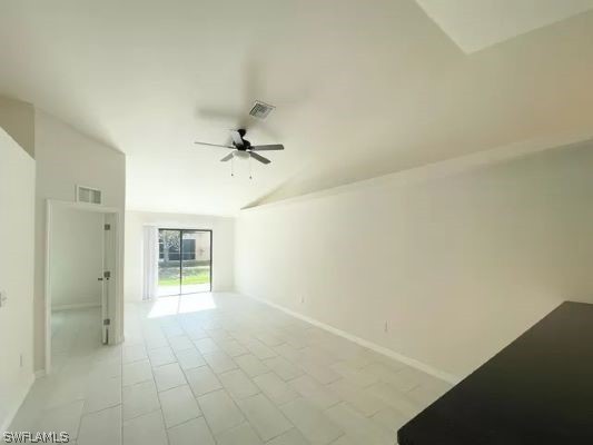 empty room with lofted ceiling, ceiling fan, and light tile flooring