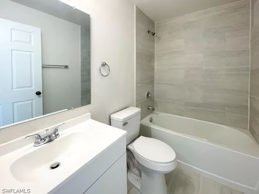 full bathroom featuring tiled shower / bath combo, vanity, and toilet