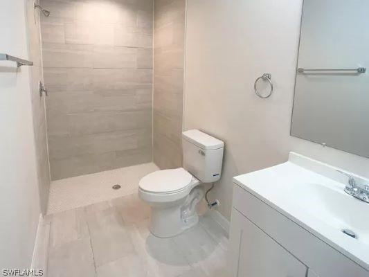 bathroom featuring vanity, tile floors, toilet, and a tile shower