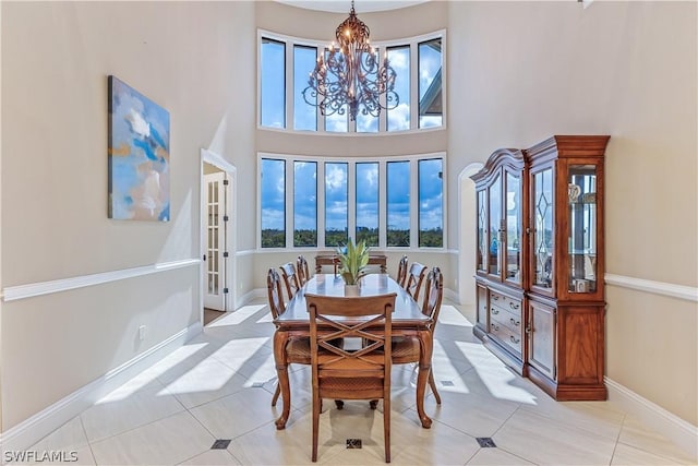 dining area with a notable chandelier, light tile patterned flooring, a high ceiling, and a wealth of natural light