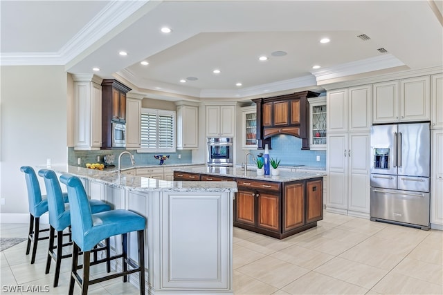 kitchen featuring light stone countertops, a kitchen island with sink, a kitchen bar, and stainless steel appliances