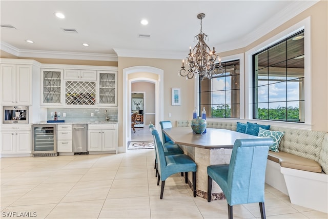 tiled dining space featuring breakfast area, ornamental molding, wine cooler, and an inviting chandelier