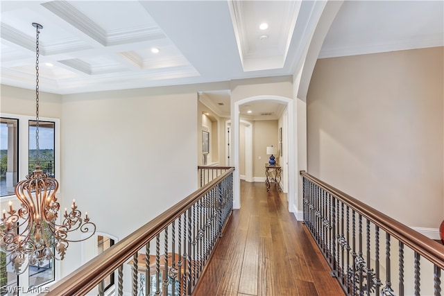 hallway featuring dark wood-type flooring, coffered ceiling, ornamental molding, beam ceiling, and a chandelier