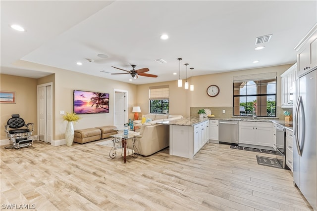 kitchen with kitchen peninsula, white cabinets, pendant lighting, and appliances with stainless steel finishes