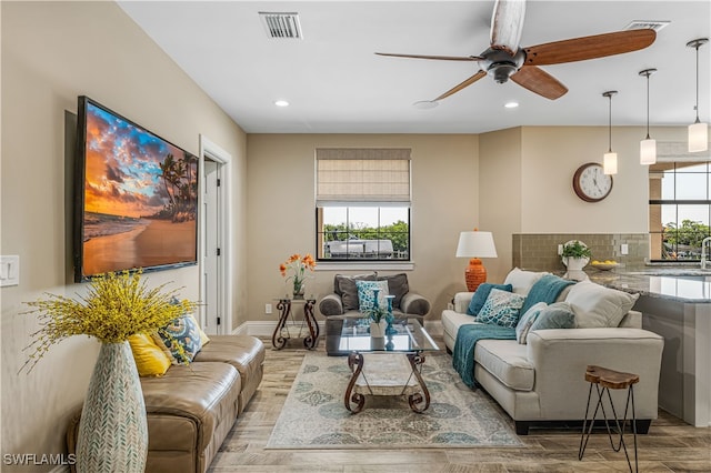 living room featuring ceiling fan, a healthy amount of sunlight, light wood-type flooring, and sink