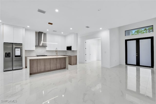 169 18th Ave NW, Naples, FL 34120 - kitchen with wall chimney exhaust hood, stainless steel refrigerator with ice dispenser, white cabinetry, modern cabinets, and marble finish floor
