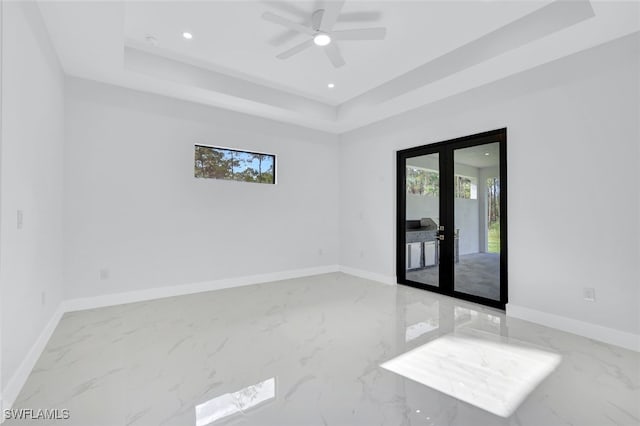 unfurnished room with ceiling fan, a raised ceiling, and french doors