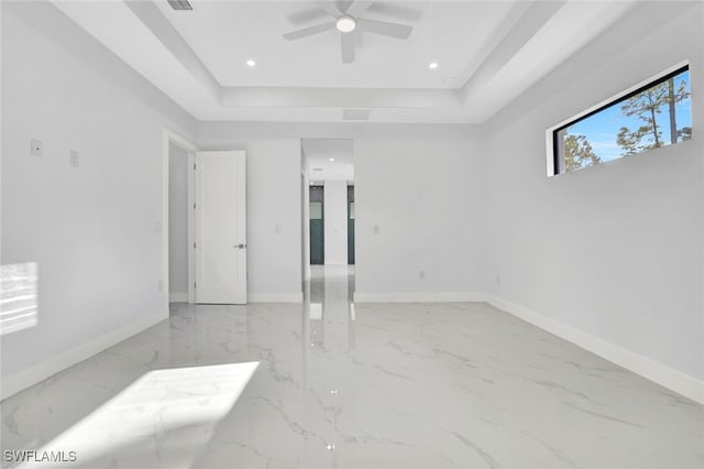 empty room featuring a raised ceiling and ceiling fan