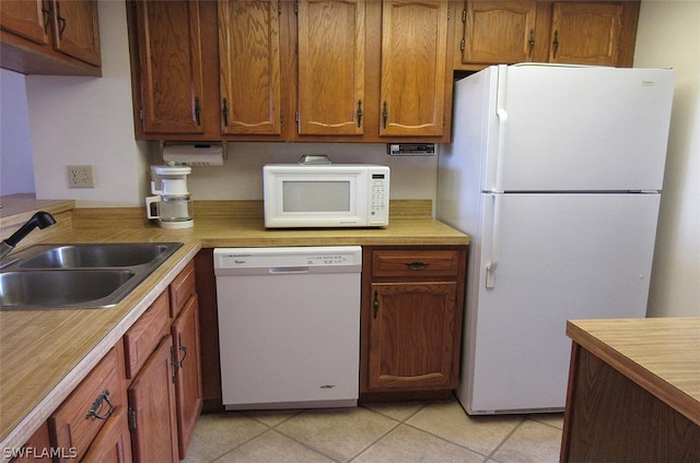 kitchen with sink, white appliances, and light tile floors