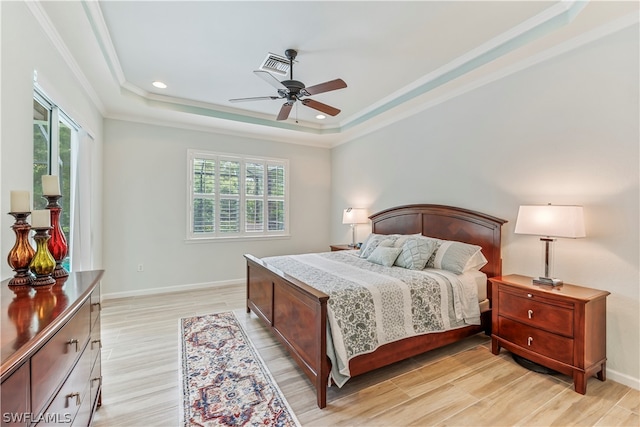 bedroom with multiple windows, a tray ceiling, ceiling fan, and light hardwood / wood-style flooring