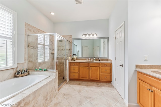 bathroom with a wealth of natural light, vanity, and separate shower and tub