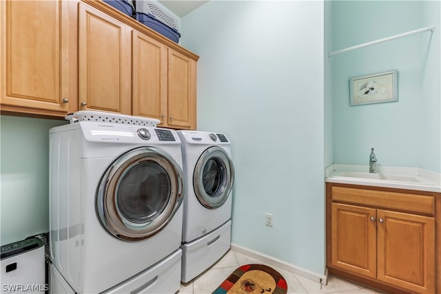 laundry area featuring washer and clothes dryer, light tile patterned flooring, sink, and cabinets