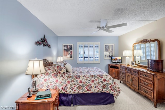 carpeted bedroom featuring multiple windows, a textured ceiling, and ceiling fan