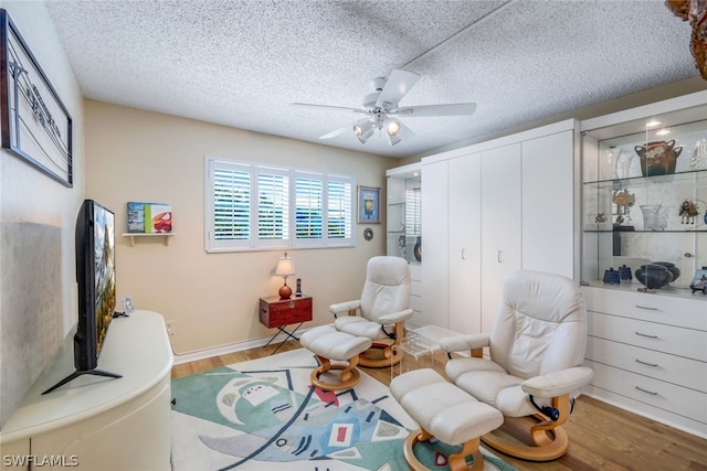 living area featuring ceiling fan, a textured ceiling, and light wood-type flooring