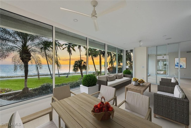 sunroom / solarium with a water view, ceiling fan, and a healthy amount of sunlight