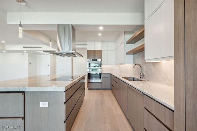 kitchen with light hardwood / wood-style flooring, island exhaust hood, a spacious island, black electric stovetop, and white cabinets