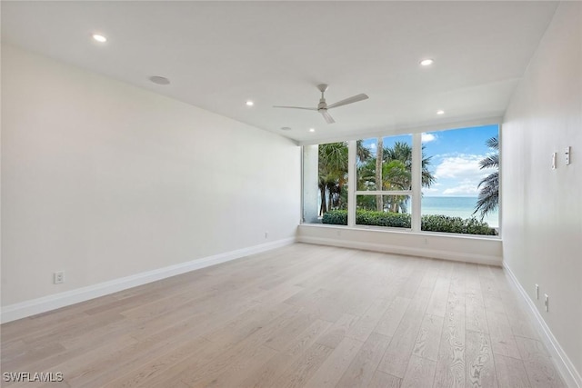 unfurnished room featuring a water view, light hardwood / wood-style flooring, and ceiling fan