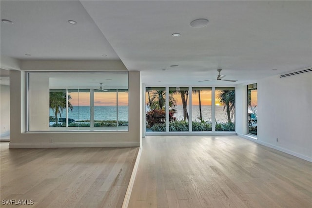 spare room featuring ceiling fan, a water view, and light wood-type flooring