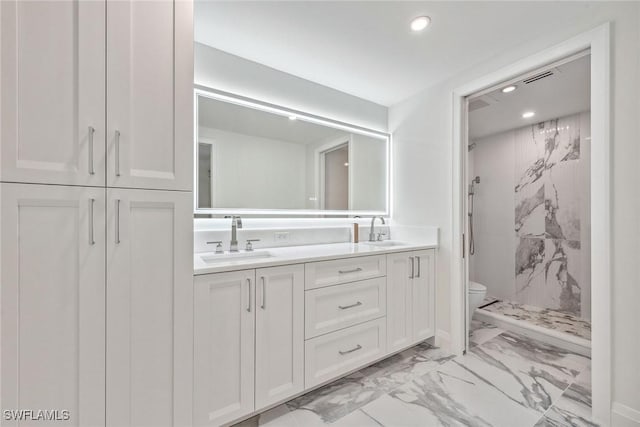 bathroom featuring a tile shower, vanity, and toilet