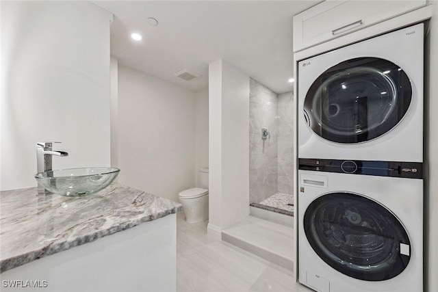 clothes washing area featuring light tile patterned floors, stacked washer / drying machine, and sink