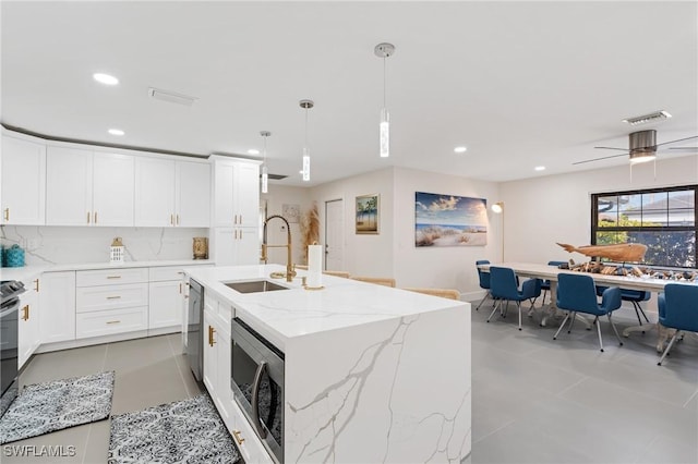 kitchen with pendant lighting, sink, stainless steel appliances, an island with sink, and white cabinets