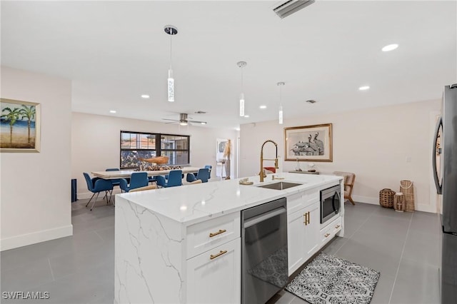 kitchen with sink, stainless steel appliances, white cabinets, a center island with sink, and decorative light fixtures