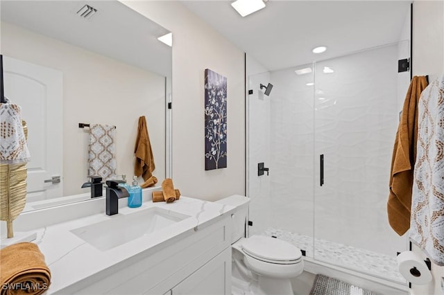 bathroom with vanity, a shower with door, and toilet