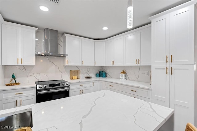 kitchen with pendant lighting, electric range, white cabinetry, and wall chimney exhaust hood