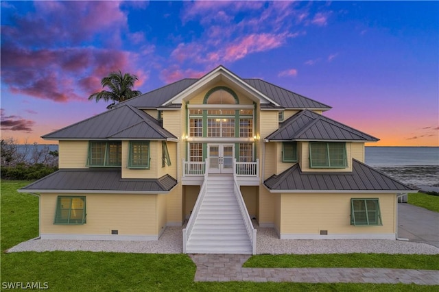 view of front of home with a yard, french doors, and a water view