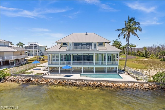 rear view of property featuring a balcony, a water view, a patio area, and a sunroom