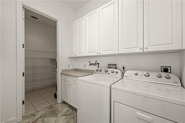 laundry area with cabinets, light tile patterned floors, and washing machine and dryer