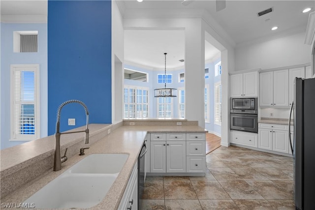 kitchen featuring white cabinetry, sink, hanging light fixtures, an inviting chandelier, and appliances with stainless steel finishes