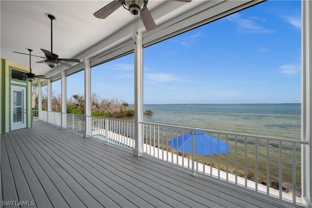 wooden deck with ceiling fan, a water view, and a beach view