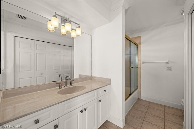 full bathroom with tile patterned floors, crown molding, bath / shower combo with glass door, toilet, and vanity