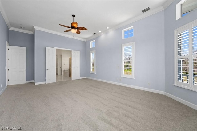 unfurnished bedroom featuring light carpet, a high ceiling, ceiling fan, and ornamental molding