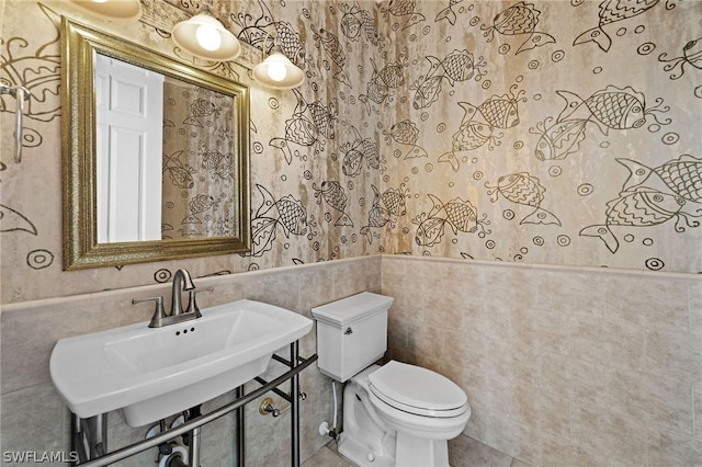 bathroom with sink, tile walls, and toilet