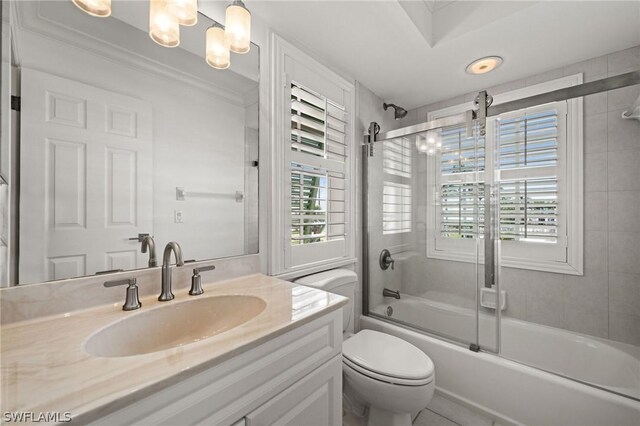 full bathroom with bath / shower combo with glass door, vanity, crown molding, a chandelier, and toilet