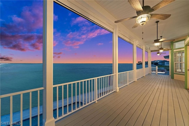 deck at dusk with ceiling fan and a water view