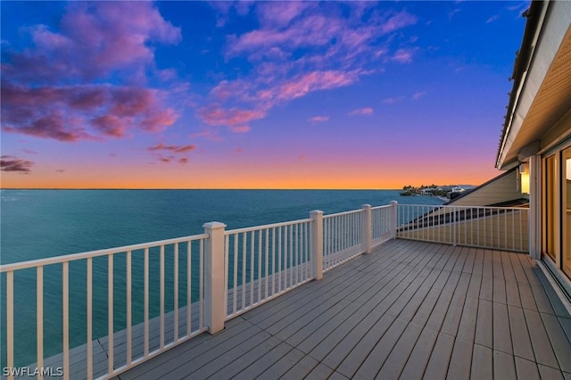 deck at dusk featuring a water view