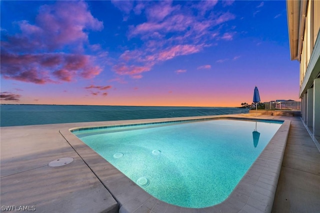 pool at dusk featuring a water view