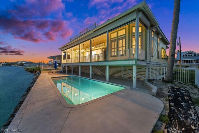 pool at dusk featuring a patio