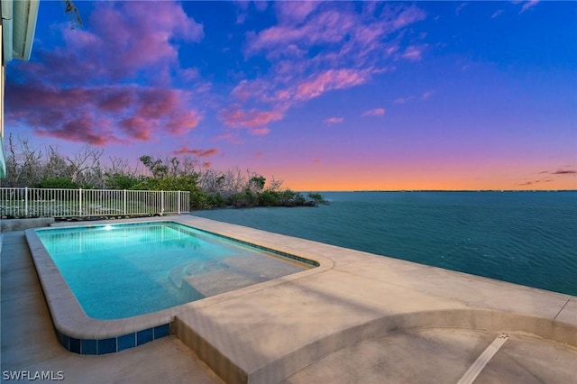 pool at dusk with a water view and a patio