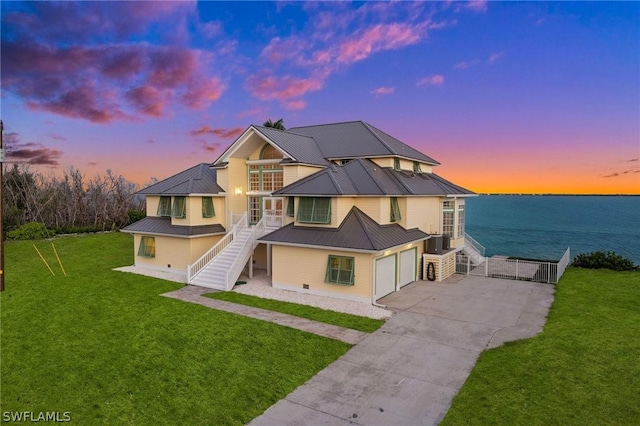 view of front of property with central AC, a yard, a water view, and a garage