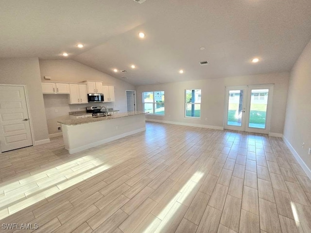 kitchen with stainless steel microwave, wood finish floors, open floor plan, white cabinets, and a sink